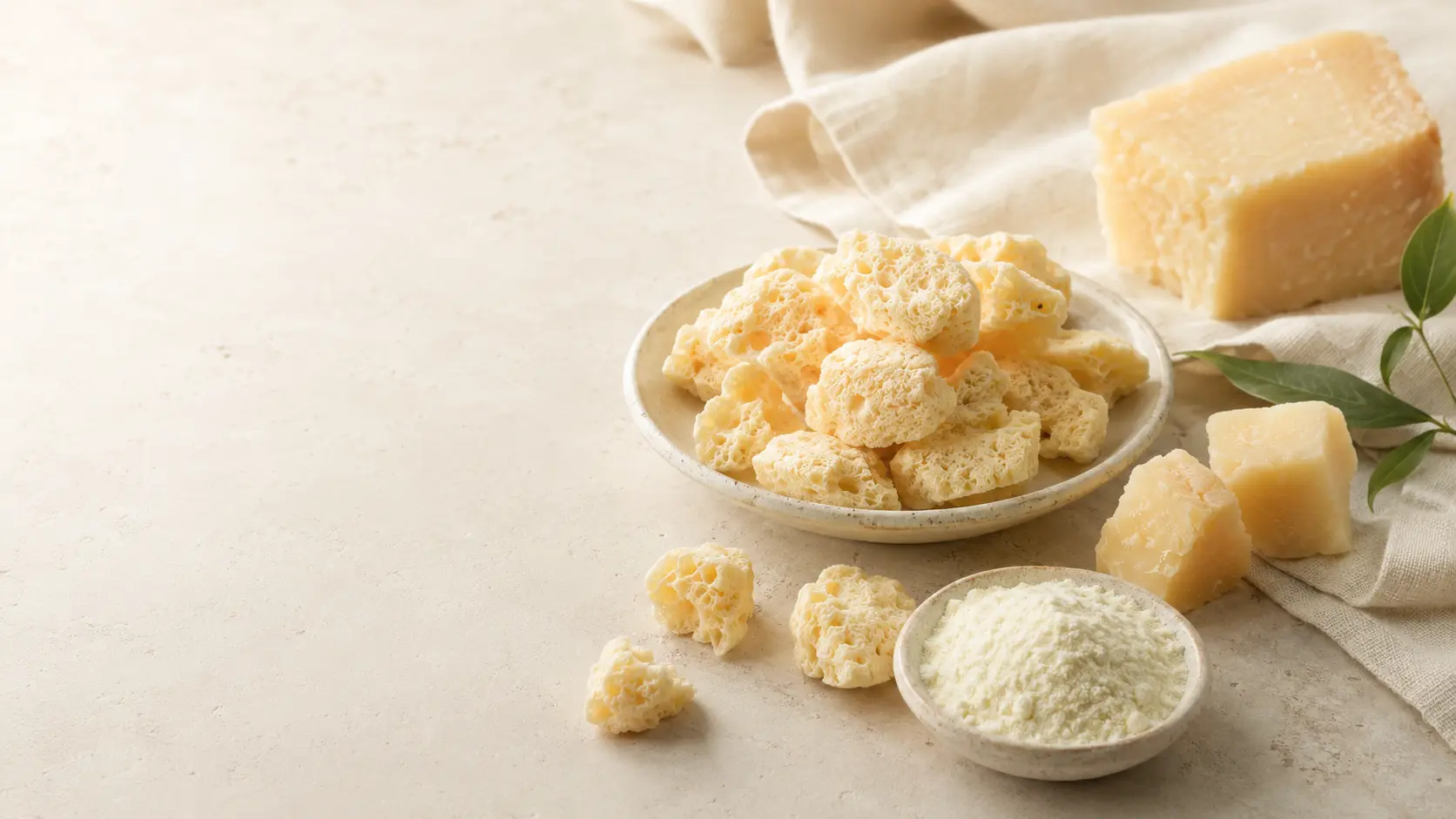 Conceptual cheese ingredients and freeze-dried pieces on a cream surface